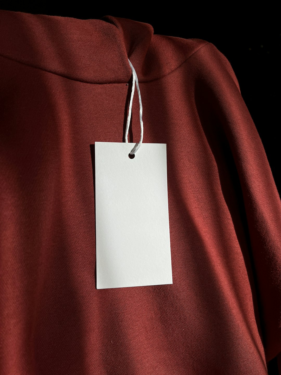 a red sweatshirt with a white tag attached to it