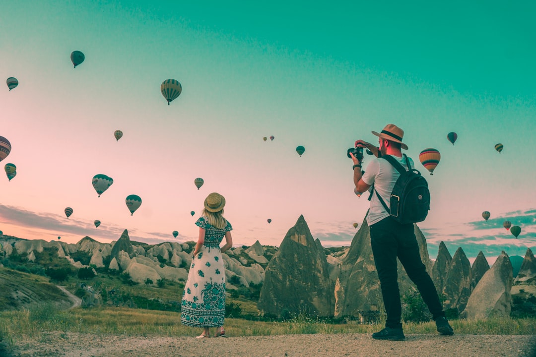 A woman and a man photographing hot air balloons over Cappadocia, Turkey
