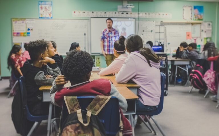 students in classroom with teacher presenting